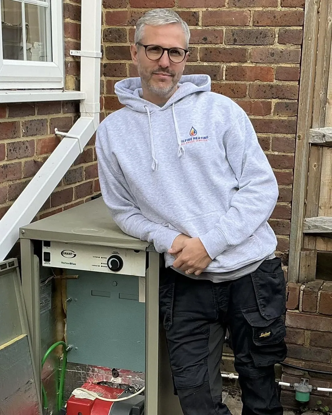 Steve Fretten beside an open Grant Vortex Blue oil boiler with the Riello burner exposed